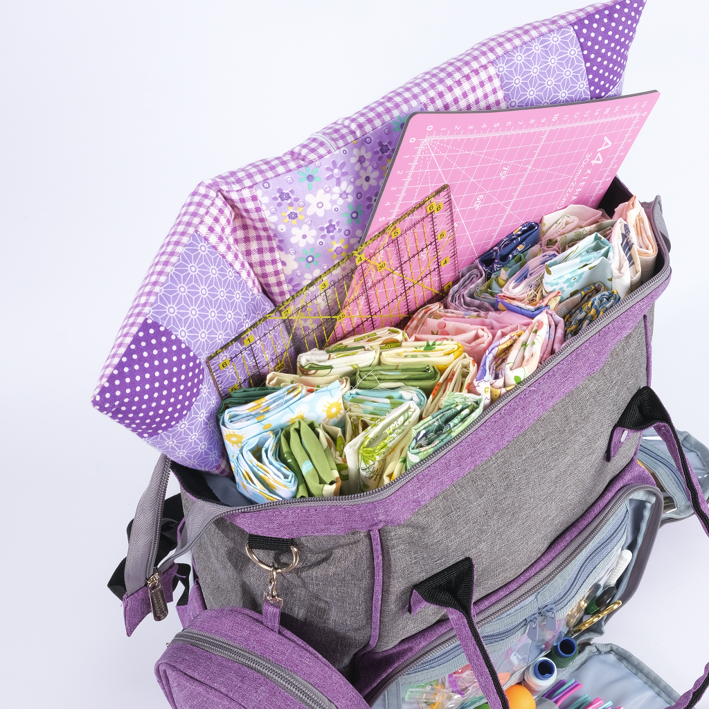 The Premium Quilting Organizer Backpack in gray and purple holds folded fabric, a cutting mat, clear rulers, and quilting tools for convenient travel-ready organization.