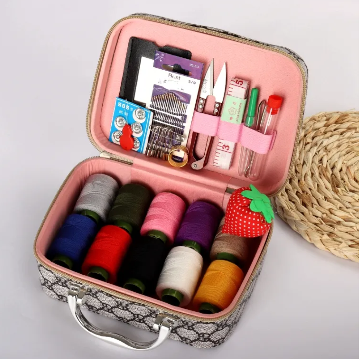 The Sewing Kit In a Stylish Box includes colorful thread spools, scissors, needles, a tomato-shaped pincushion, measuring tape, and other sewing tools neatly organized in a pink-lined case.