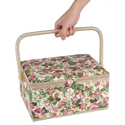 A hand holds an Extra Large Vintage Sewing Basket adorned with a floral pattern, featuring a woven handle and exuding timeless aesthetics.